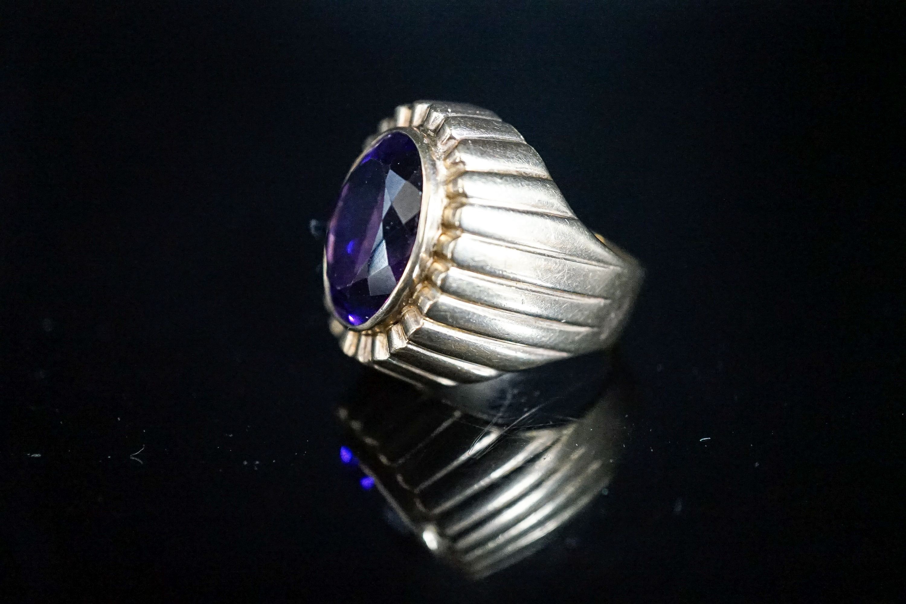 A yellow metal and oval cut amethyst set dress ring, with fluted setting, size Q/R, gross 17 grams.